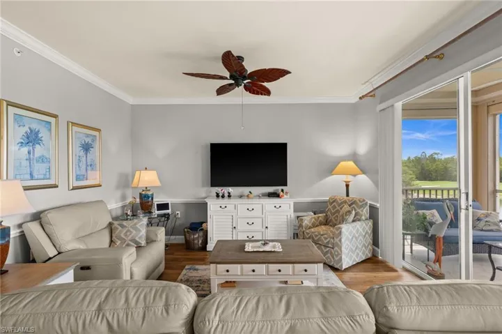 Living space featuring wood-finish flooring, crown molding, and a ceiling fan