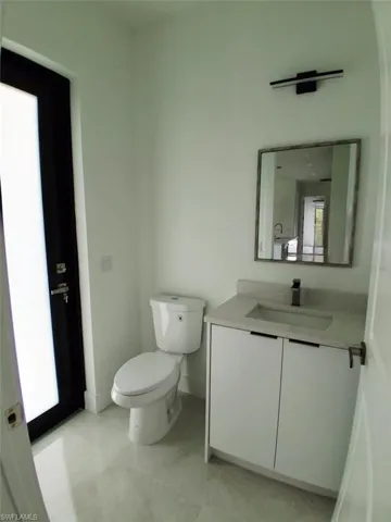 Half bathroom with vanity and toilet and door to patio