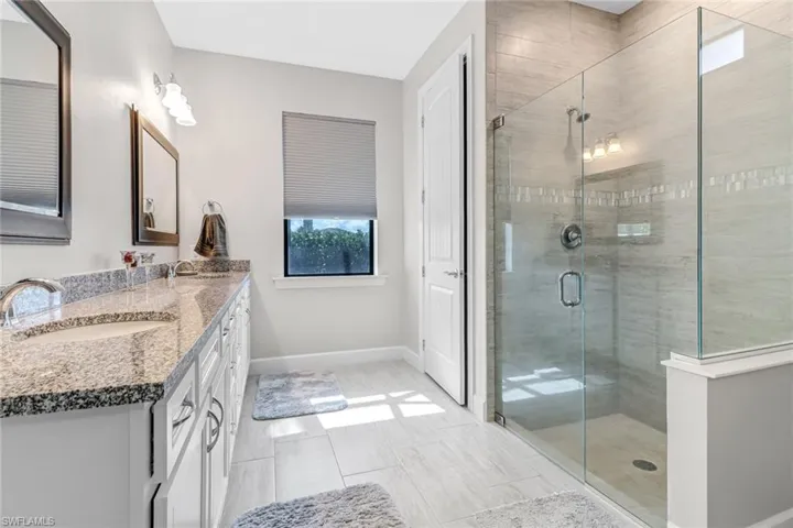 Bathroom with double vanity, tile flooring, and a shower with shower door