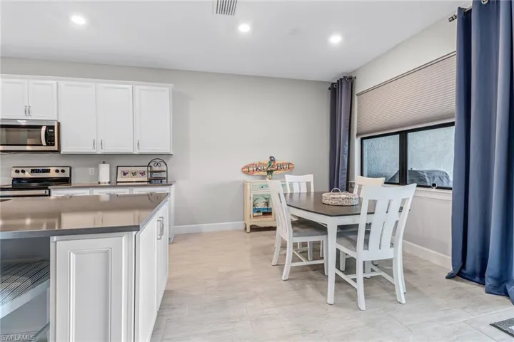Kitchen with stainless steel appliances, white cabinets, a center island, and light tile floors
