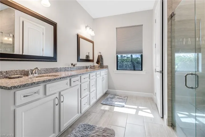 Bathroom featuring double sink vanity and a shower with door