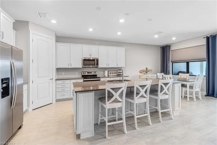 Kitchen with appliances with stainless steel finishes, white cabinetry, sink, and a center island with sink