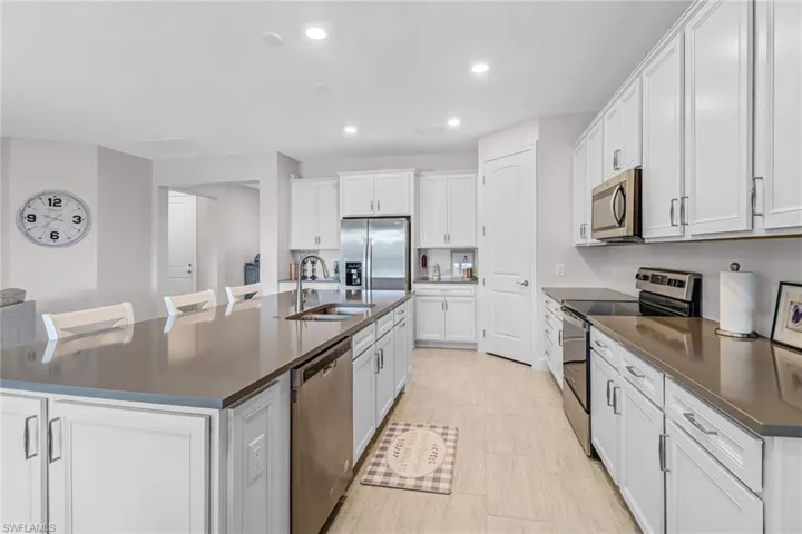 Kitchen with sink, white cabinets, a center island with sink, and stainless steel appliances