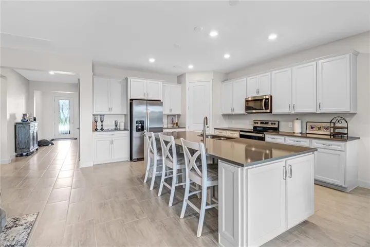 Kitchen featuring sink, a breakfast bar, a kitchen island with sink, white cabinetry, and appliances with stainless steel finishes