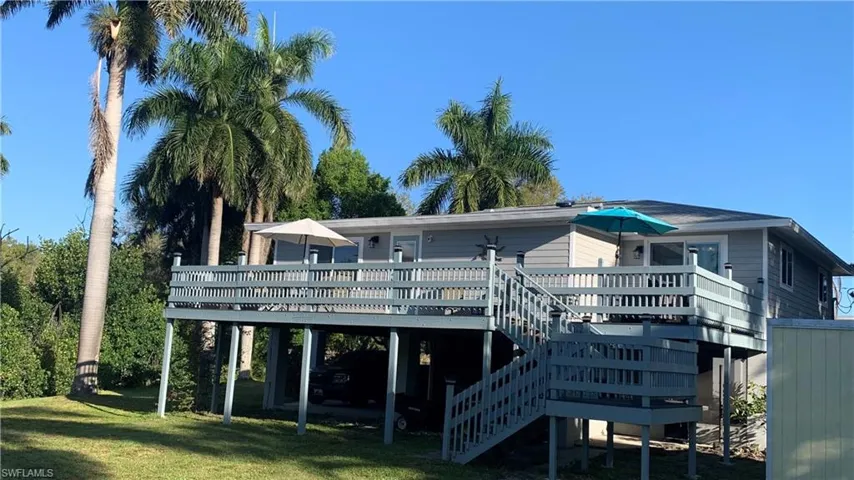 Back of property with a deck, a yard, and a carport