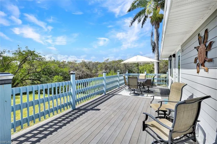 Deck featuring outdoor dining space, a yard, and view of wooded area