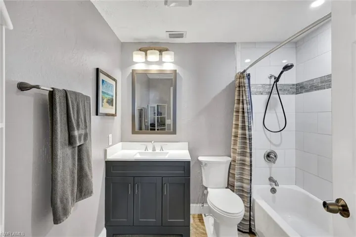 Bathroom featuring vanity, a textured wall, and shower / bath combination with curtain