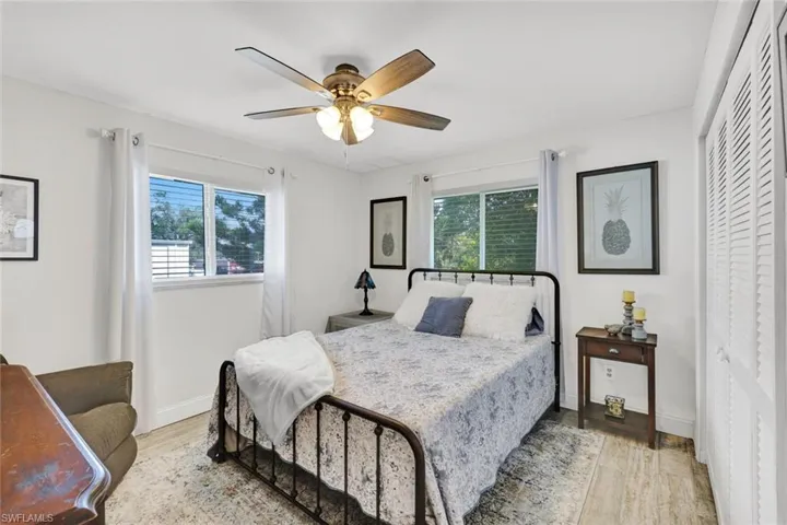 Bedroom with light wood-type flooring, multiple windows, ceiling fan, and a closet
