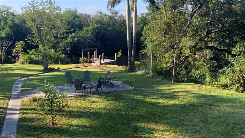 View of grassy yard featuring a patio area and a fire pit