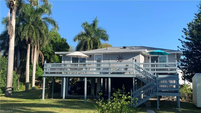 Rear view of house with a wooden deck and a lawn