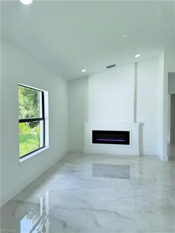 Unfurnished living room featuring light marble finish floors, a glass covered fireplace, and recessed lighting