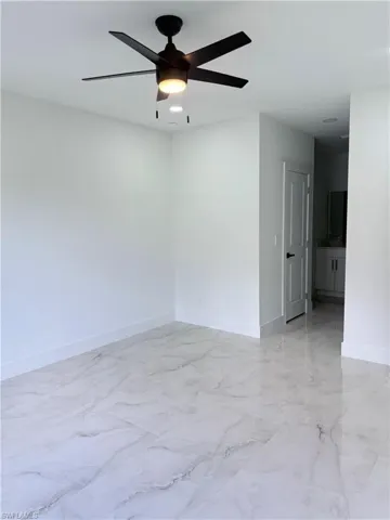 Empty room featuring light marble finish flooring and ceiling fan