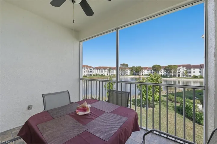 Sunroom / solarium featuring a balcony, a ceiling fan, outdoor dining area, and a water view