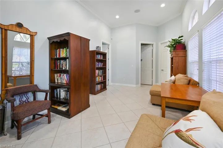 Living area with light tile patterned floors, ornamental molding, a high ceiling, and recessed lighting