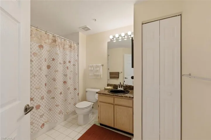 Full bath with a closet, vanity, a shower with shower curtain, and light tile patterned flooring