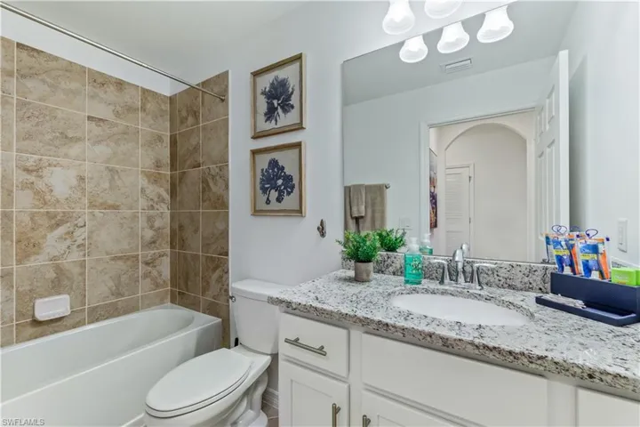 Full bathroom featuring toilet, tiled shower / bath, and vanity with extensive cabinet space