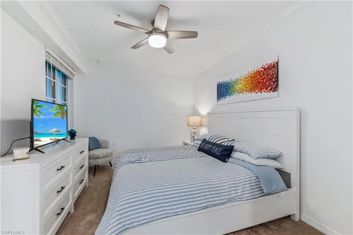 Carpeted bedroom with ornamental molding and ceiling fan