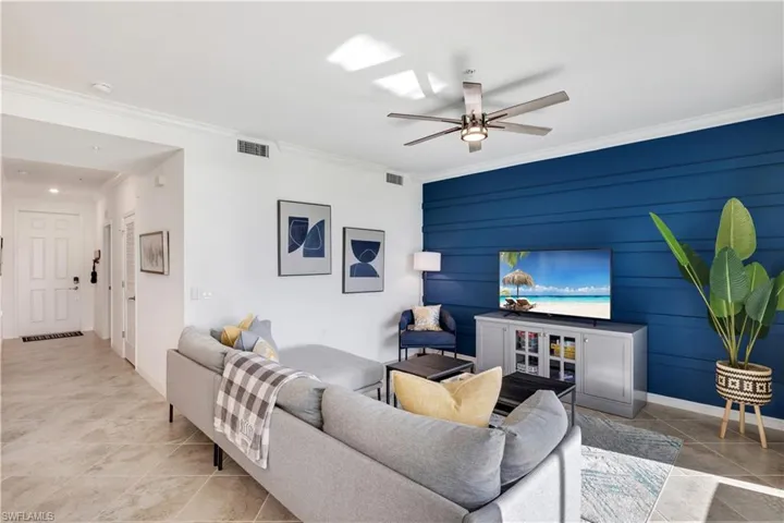 Tiled living room featuring crown molding and ceiling fan
