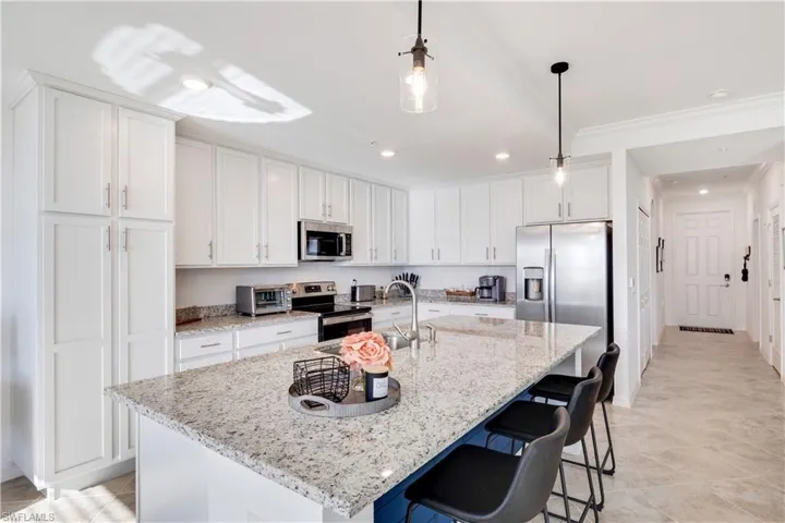 Kitchen featuring an island with sink, white cabinets, and stainless steel appliances