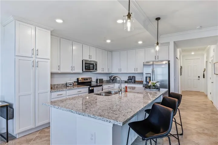 Kitchen with white cabinetry, appliances with stainless steel finishes, sink, and pendant lighting