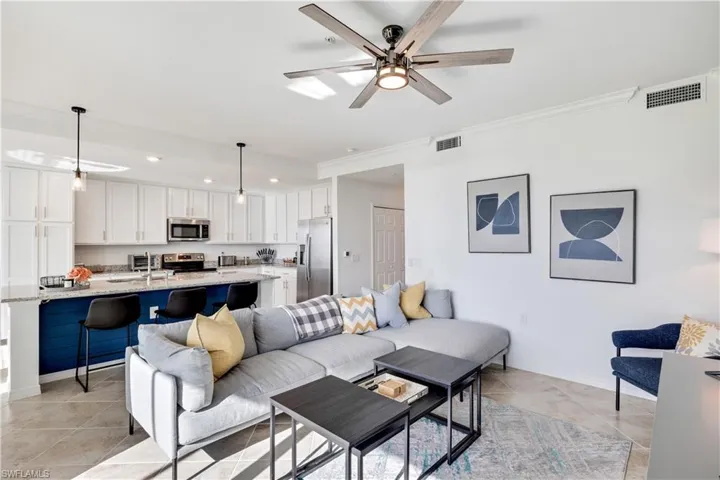 Living room featuring sink, ornamental molding, ceiling fan, and light tile floors