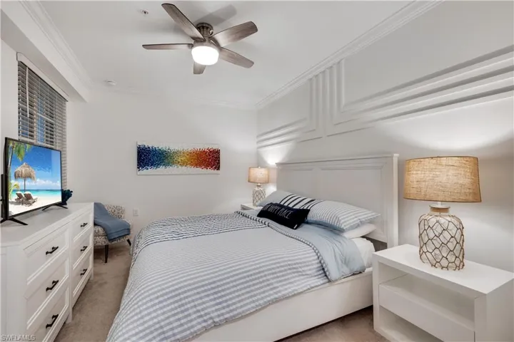 Carpeted bedroom with ceiling fan and crown molding
