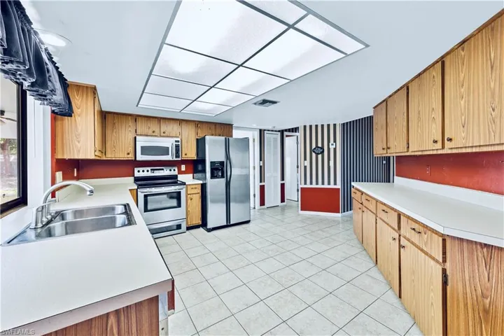 Kitchen with light tile patterned floors, sink, and appliances with stainless steel finishes