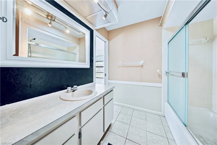 Bathroom featuring tile patterned flooring, vanity, and combined bath / shower with glass door