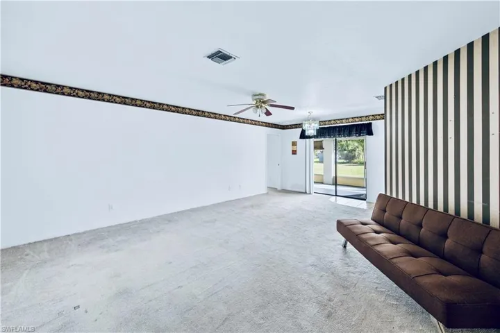 Unfurnished living room featuring ceiling fan and carpet
