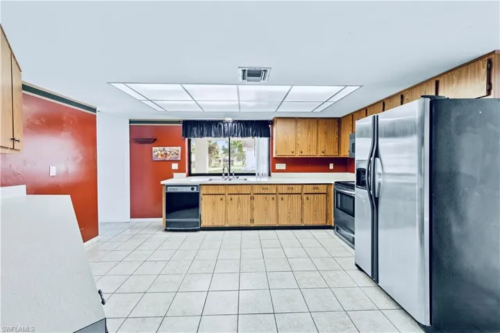 Kitchen featuring light tile patterned flooring, sink, and appliances with stainless steel finishes