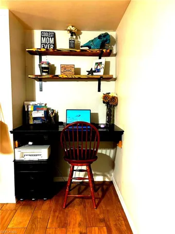 Office space with built in desk and wood shelving.