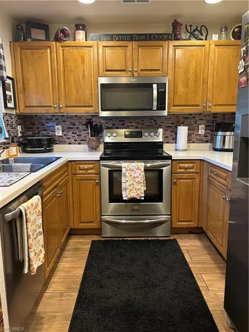Kitchen with stainless steel appliances, Wood grain Cabinetry and Corion Countertops