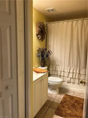 Bathroom with vanity, shower / tub combo, and tile flooring