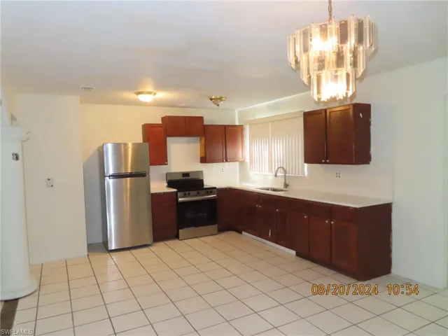 Kitchen with light tile patterned floors, appliances with stainless steel finishes, sink, and hanging light fixtures