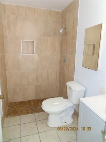 Bathroom with tile patterned floors, vanity, tiled shower, and toilet