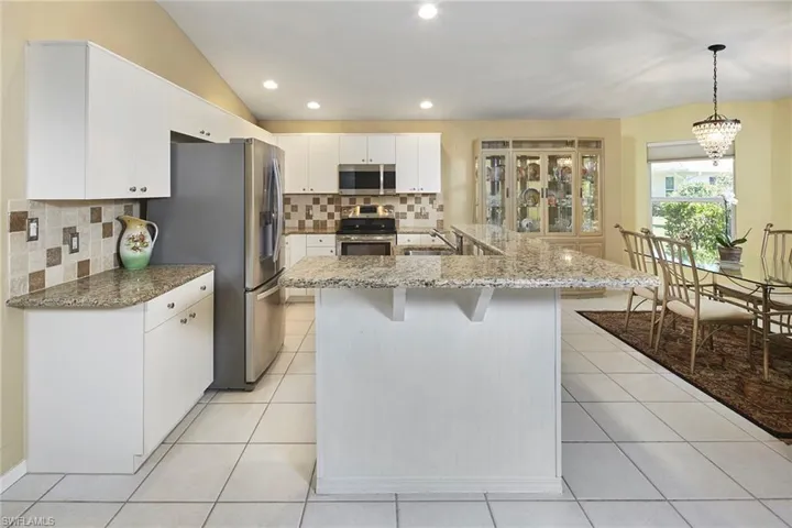 Kitchen featuring a breakfast bar, decorative backsplash, white cabinetry, recessed lighting, and stainless steel appliances