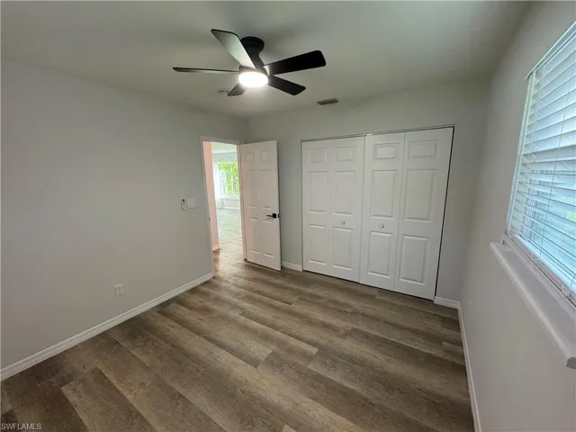 Unfurnished bedroom with ceiling fan, dark wood-style flooring, and a closet