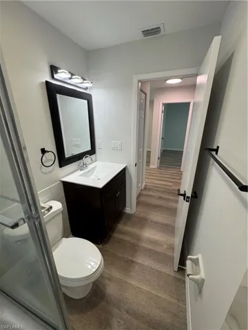 Full bathroom featuring vanity, a stall shower, and dark wood-style flooring