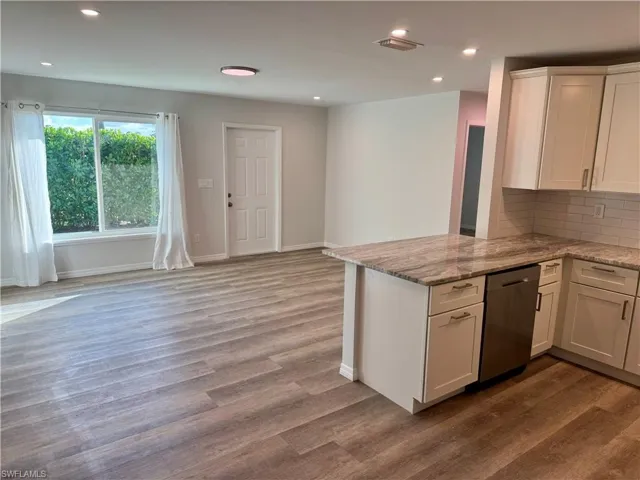 Kitchen featuring white cabinetry, light stone countertops, recessed lighting, dishwasher, and a peninsula