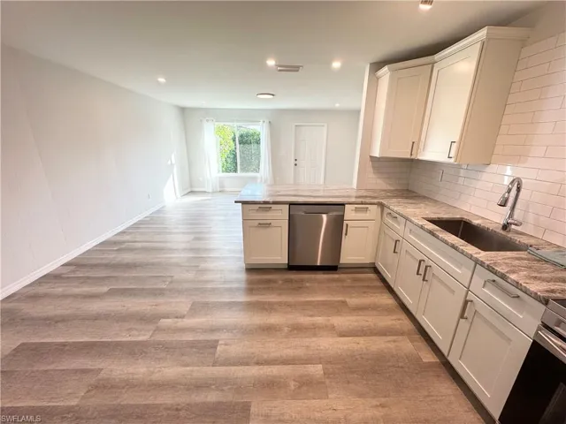 Kitchen with white cabinets, appliances with stainless steel finishes, a peninsula, light stone countertops, and recessed lighting