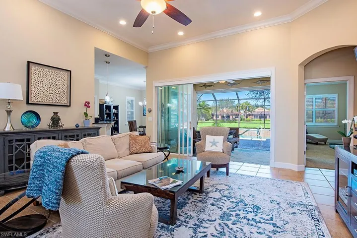 Living area with ornamental molding, a ceiling fan, light tile patterned floors, recessed lighting, and arched walkways