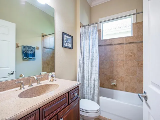 Bathroom featuring vanity, shower / bath combination with curtain, crown molding, and a textured wall