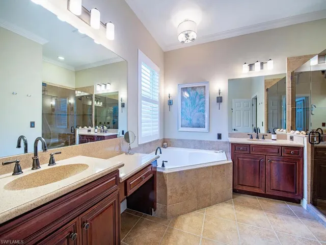 Full bathroom featuring a bath, two vanities, ornamental molding, a shower stall, and light tile patterned floors