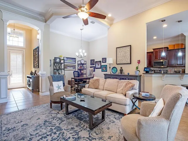 Tiled living area featuring a chandelier, a ceiling fan, ornamental molding, and arched walkways