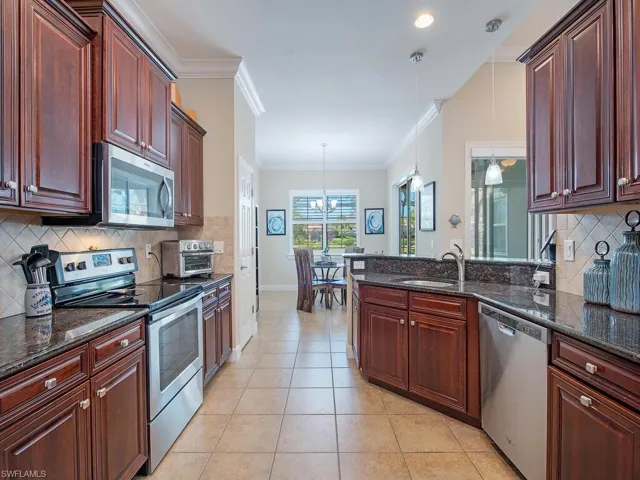 Kitchen with decorative backsplash, stainless steel appliances, dark stone counters, a peninsula, and crown molding