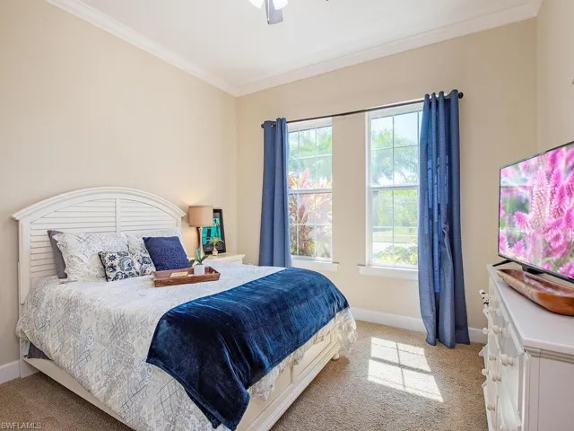 Bedroom with light carpet, ornamental molding, and a ceiling fan