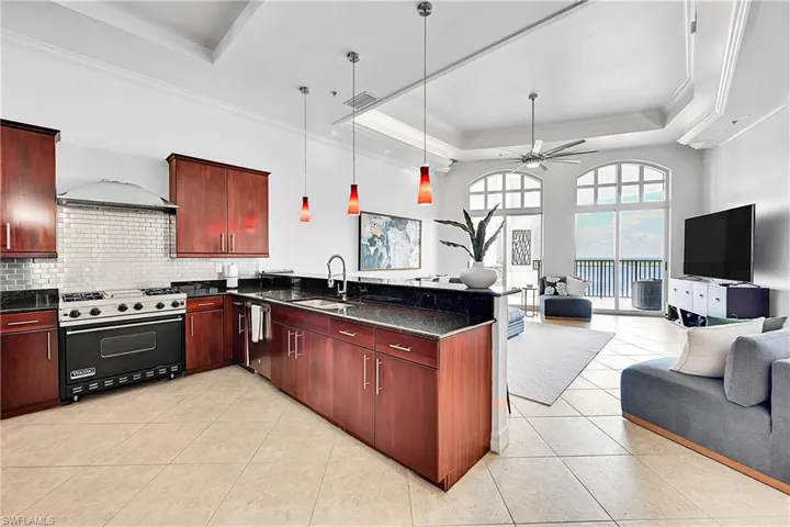 Kitchen with range with gas cooktop, a sink, open floor plan, a raised ceiling, and stainless steel dishwasher