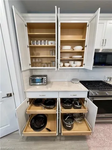 Kitchen view of appliances with stainless steel finishes, white cabinetry, light stone counters, and light wood finished floors