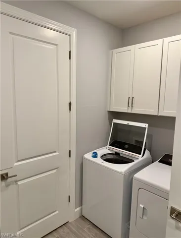 Laundry area with wood tiled floors, cabinet space, and independent washer and dryer
