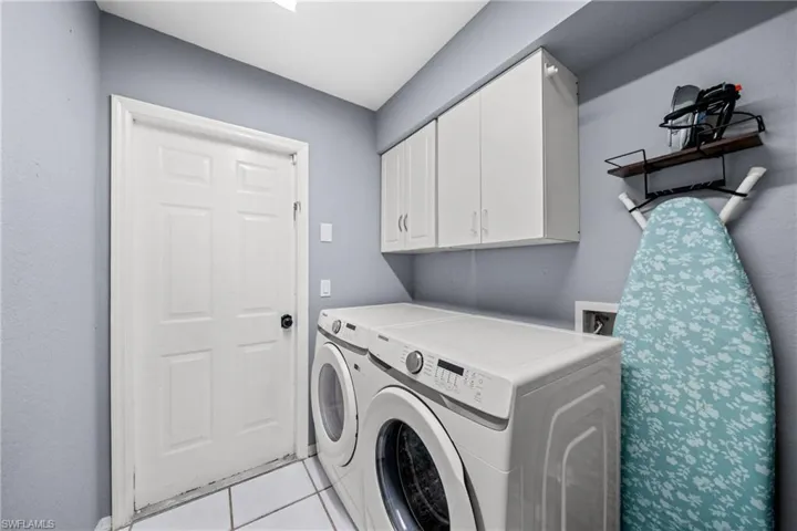 Laundry room with independent washer and dryer, cabinet space, and light tile patterned flooring